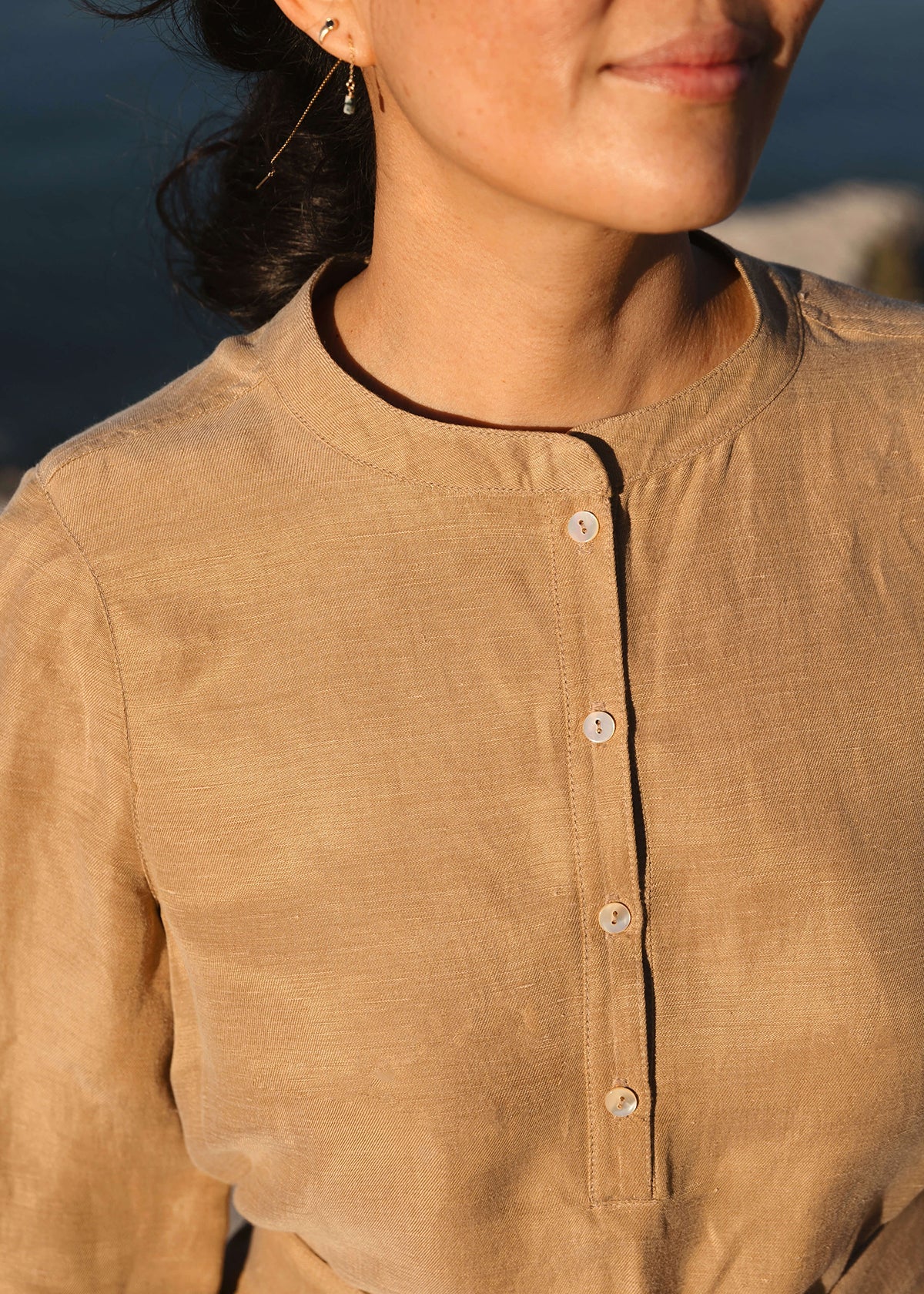 Woman wearing a Tunic style dress with pockets, a detached belt and high side slits, in a light brown camel color.