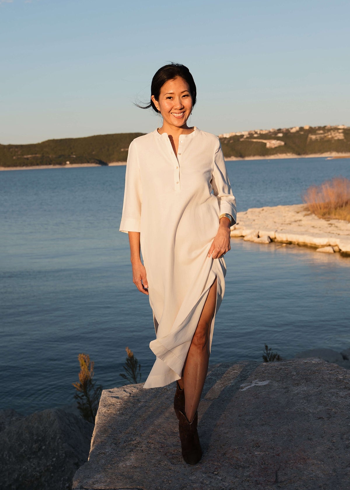 Woman wearing a Tunic style dress with pockets, and high side slits, in white.
